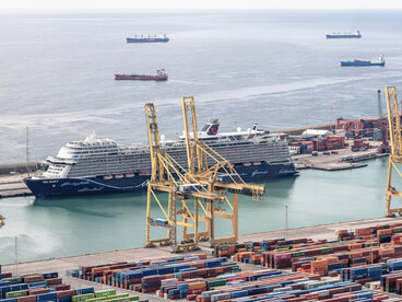 A cargo ship being loaded at a port during the day, illustrating activity along a major trade corridor