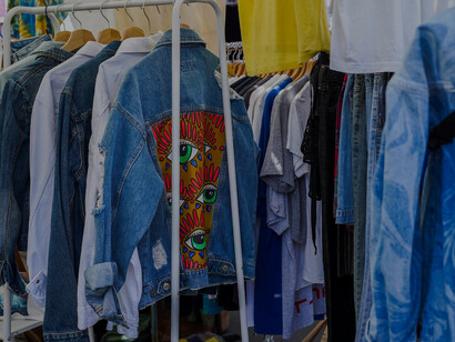 Secondhand fashion on display at a flea market, with clothes hanging in a colorful, textured close-up that highlights reuse and individuality