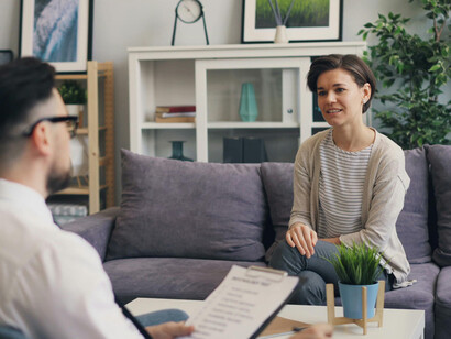 A man and a woman are sitting on a couch, talking to each other