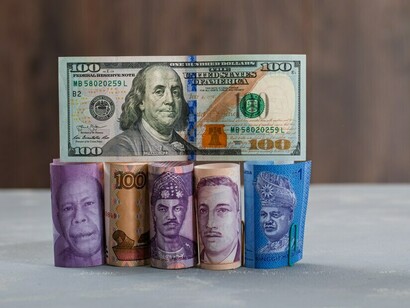 Assorted currency bills scattered across a plaster and wooden table