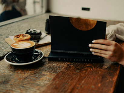 A woman relaxing with a book and good food, showing how a different world of serenity is within our reach