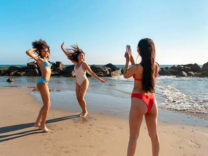 Young women laughing and relaxing by the sea in colorful bikinis