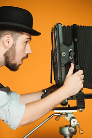 A young man with a retro camera is captured alongside film projector, movie screen, film camera, and film editing equipment, embodying the essence of cinematic artistry and production