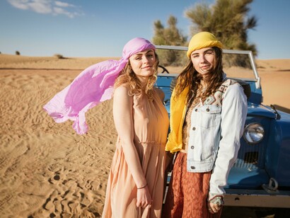 Desert safari in the UAE, with two women posing next to a blue Land Rover