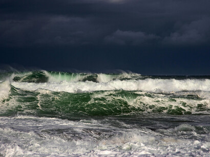Large waves rising under a cloudy sky, depicting a tsunami following an earthquake