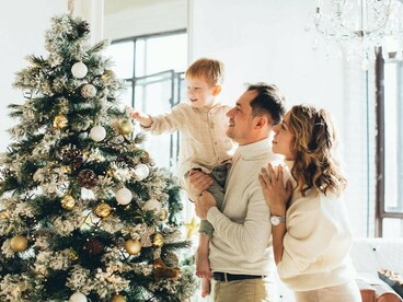 A family joyfully decorates the Christmas tree, filling the room with festive cheer