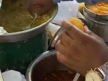 Man preparing gol gappa at a bustling street food stall in Mumbai, India