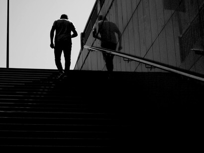 Black and white silhouettes of men ascending subway steps, a stark image of loneliness