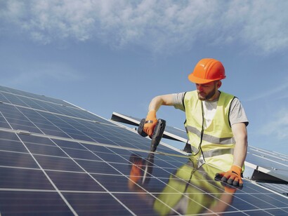 An electrician installing a solar panel on a rooftop