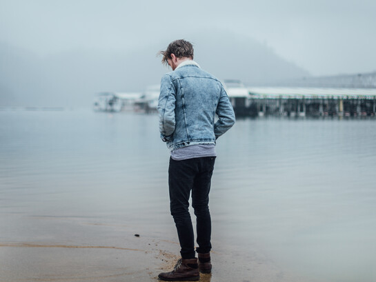 Man standing alone on the beach, looking at his reflection 