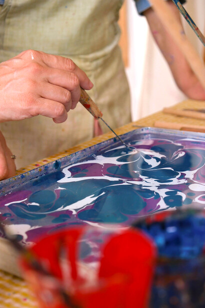 Colorful Ebru painting in progress in a bright, naturally lit artist studio