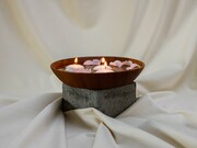 Tigela de madeira com velas acesas e pétalas