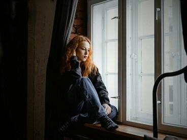 A woman staring out at the world she longs to enter, echoing the silent wish for connection