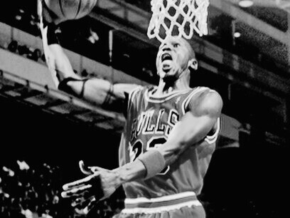 Michael Jordan, l'icône du basket, en plein vol lors d’un match. Sa légende vivante dépasse les terrains de jeu, incarnant l’apogée du sport et la culture du vintage à travers ses performances inoubliables