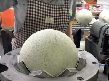 A woman is engaged in the process of producing footballs