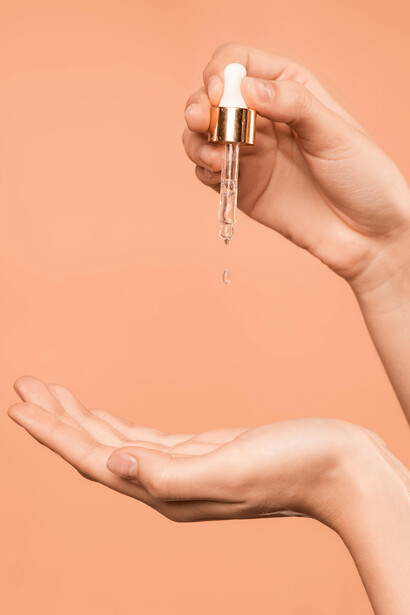 Person holding a serum bottle for skincare and beauty