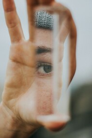 A woman's eye, reflected on a glass shard she's holding