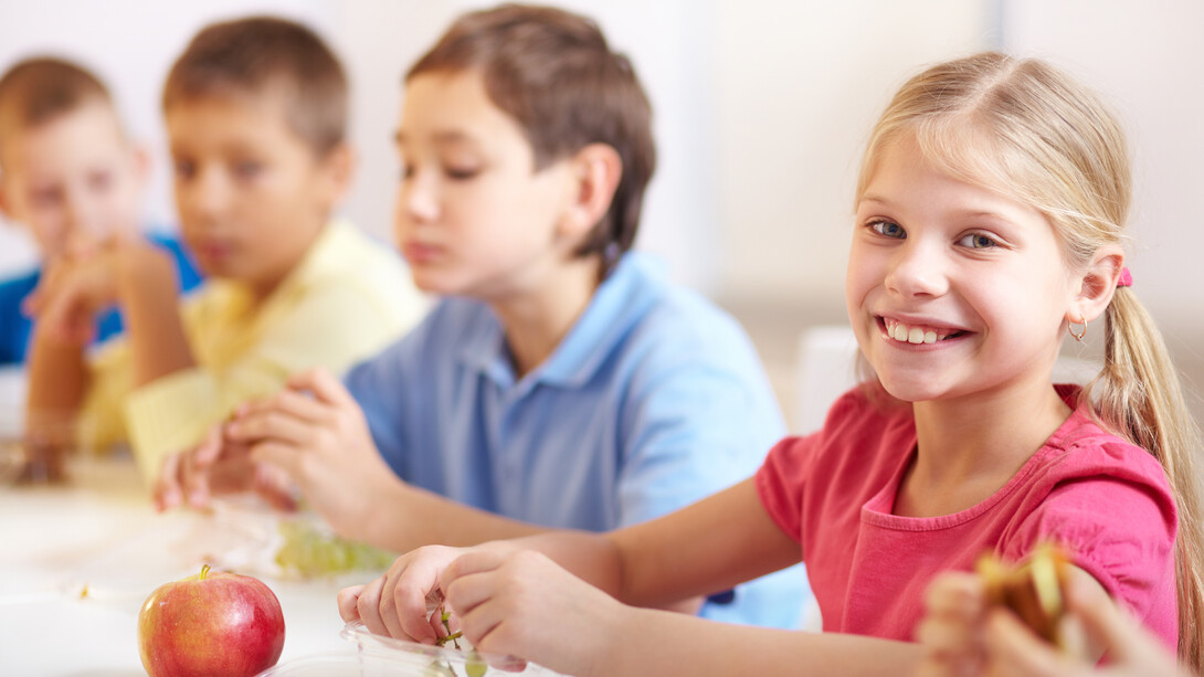 Smiling girl enjoying grapes as part of a healthy school lunch