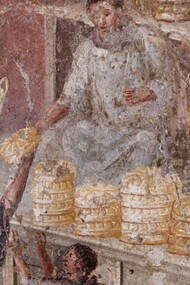 Affresco comunemente interpretato come un "panettiere che vende il suo pane"; in realtà si tratta di una donazione di pane, probabilmente fatta per propaganda personale ed a fini politici; infatti l'uomo veste una toga, dunque non è un panettiere e men che mai una persona umile. Da Pompei, VII, 3, 30. MANN - Museo Archeologico Nazionale di Napoli, Italia
