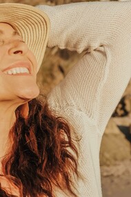 A smiling woman with a hat relishes in the sunlught