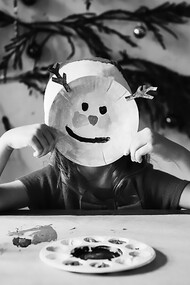 "A little girl wears a reindeer mask, her face beaming with a joyful smile