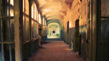 A deserted indoor hallway in a ruined, deteriorating house