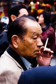 An elderly yakuza member smoking outside, his expression calm and contemplative