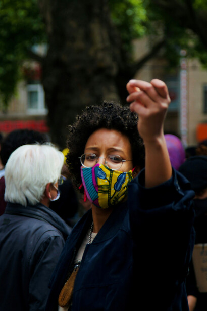 A woman in a black jacket and yellow mask protesting for equality in Cologne, Germany