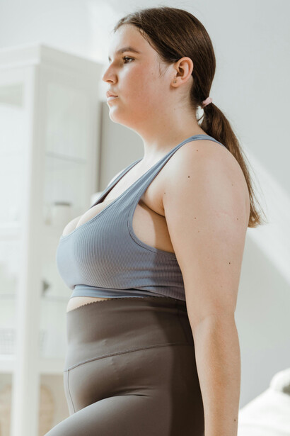 A woman in brown leggings performs strength training with a dumbbell