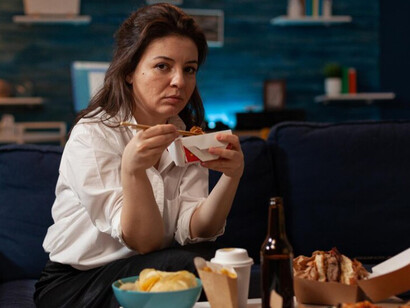 A woman sitting on the couch, binge eating while watching TV