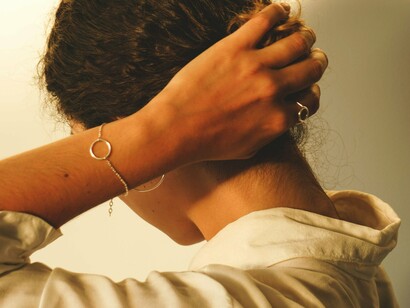 With her hand placed at the base of her neck, this woman demonstrates how a morning stretch can target stress held in the shoulders and spine