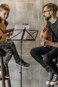 Professor de violão clássico dando aula a um jovem aluno