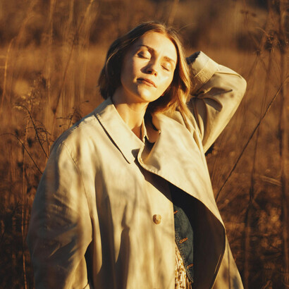 A woman enjoys a peaceful autumn evening in a sunlit field near Brevard, North Carolina, US