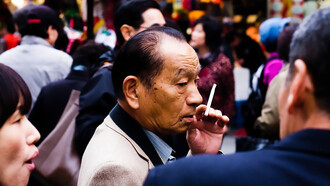 An elderly yakuza member smoking outside, his expression calm and contemplative