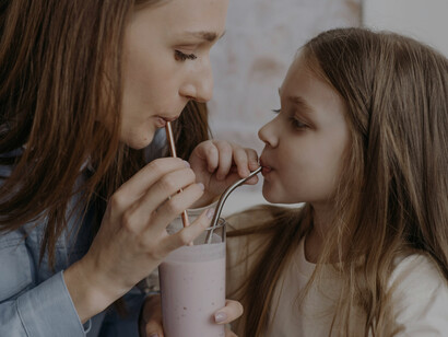 A woman and a child enjoy preparing and sharing a vibrant rainbow smoothie, showing the fun of making smoothies together