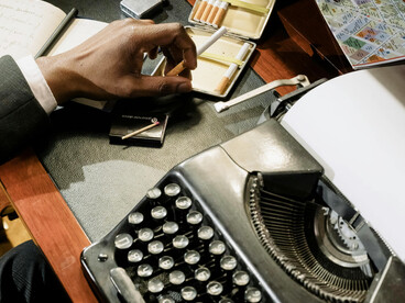 A man typing on a typewriter at his desk