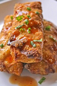 Crispy Philly cheesesteak egg rolls, drizzled with a sweet and savory glaze, garnished with fresh green onions — the perfect fusion of comfort and crunch
