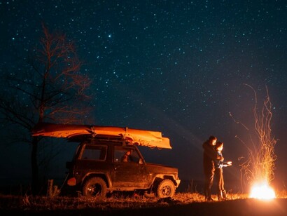 A couple illuminated by firelight in the vast darkness of the desert, symbolising the intimacy and stillness of remote landscapes