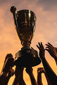 Celebrate victory with a compelling image of hands lifting a football cup, symbolizing triumph and success in soccer championships