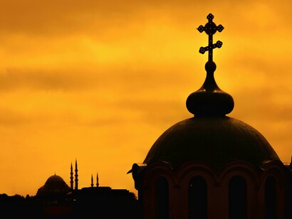 Silhouetted bell towers and church domes set against a golden sunset sky, Turkey