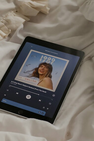 A tablet sitting on a bed next to a cup of coffee, Playing Taylor Swift