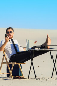 Businessman working on a laptop in a desert, highlighting flexible work arrangements and summer productivity