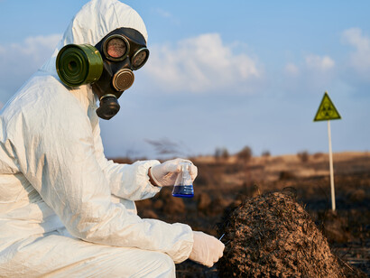 A scientist surveys a burned field during research work at a nuclear-affected site