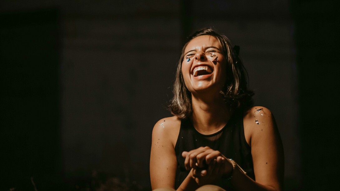 A photo of a woman laughing in a black top, capturing her funny and wonderfully weird energy