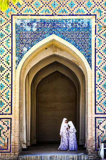 Women standing at the ornamented entrance of a mosque in Bukhara, Uzbekistan, showcasing the country’s rich architectural and cultural heritage