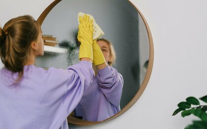 Une femme nettoyant un miroir soigneusement et se concentrant sur la tâche