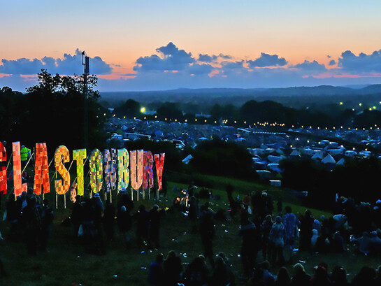 The Glastonbury Festival 2011 captured at night, glowing with lights, music, and the energy of thousands of festivalgoers