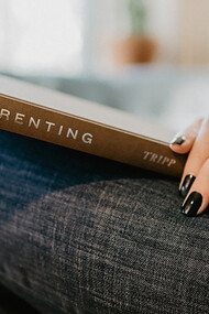 A nurturing woman engrossed in a parenting book, finding guidance within its pages