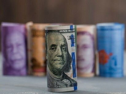A variety of currency bills arranged on a plaster and wooden table