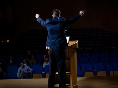 Un politico sul palco, arringa il pubblico in un auditorium